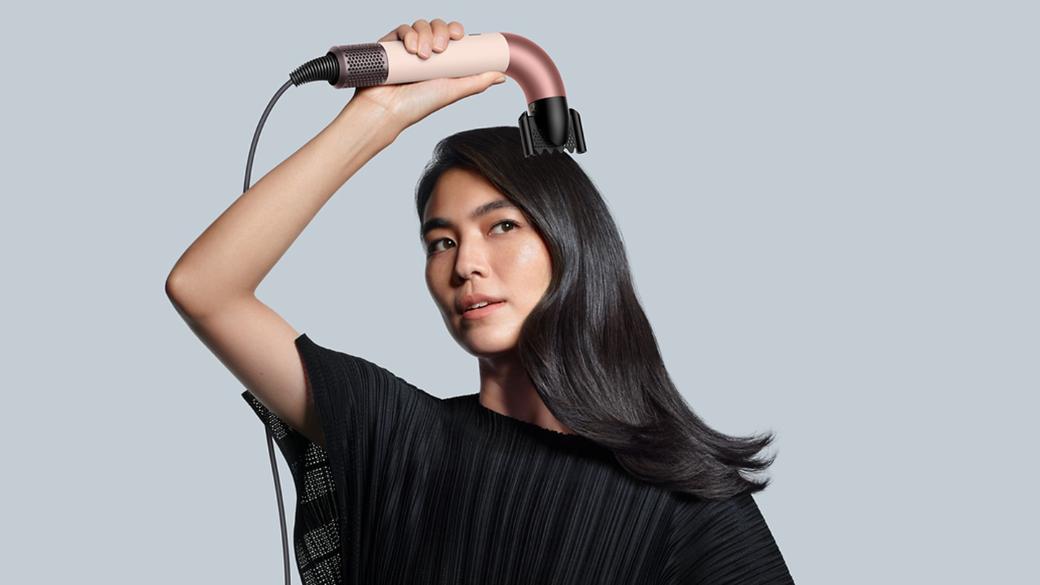 Female model holding the Dyson Supersonic r with the Smoothing Nozzle attachment.