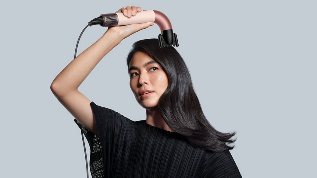 Female model holding the Dyson Supersonic r with the Smoothing Nozzle attachment.
