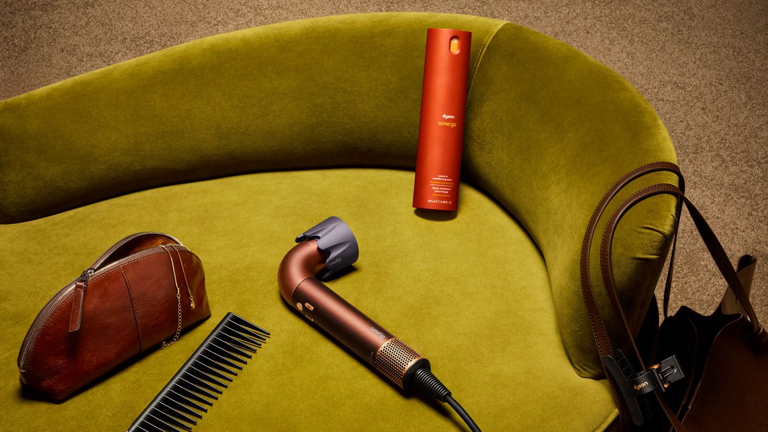 Dyson Supersonic R hair dryer on a chair with Dyson Omega leave-in conditioning spray.