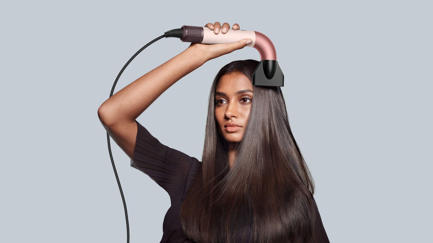 Female model holding the Dyson Supersonic r with the Pro concentrator attachment.