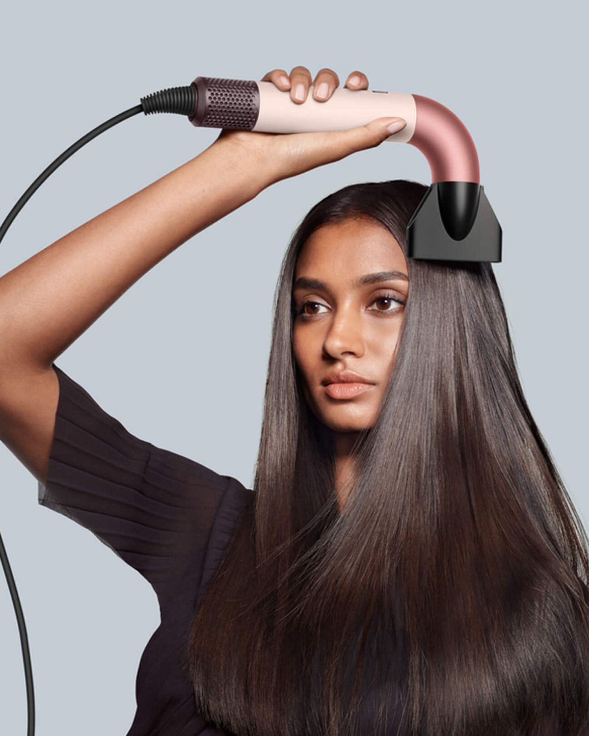 Modelo sosteniendo el Dyson Supersonic r con el accesorio concentrador Pro.