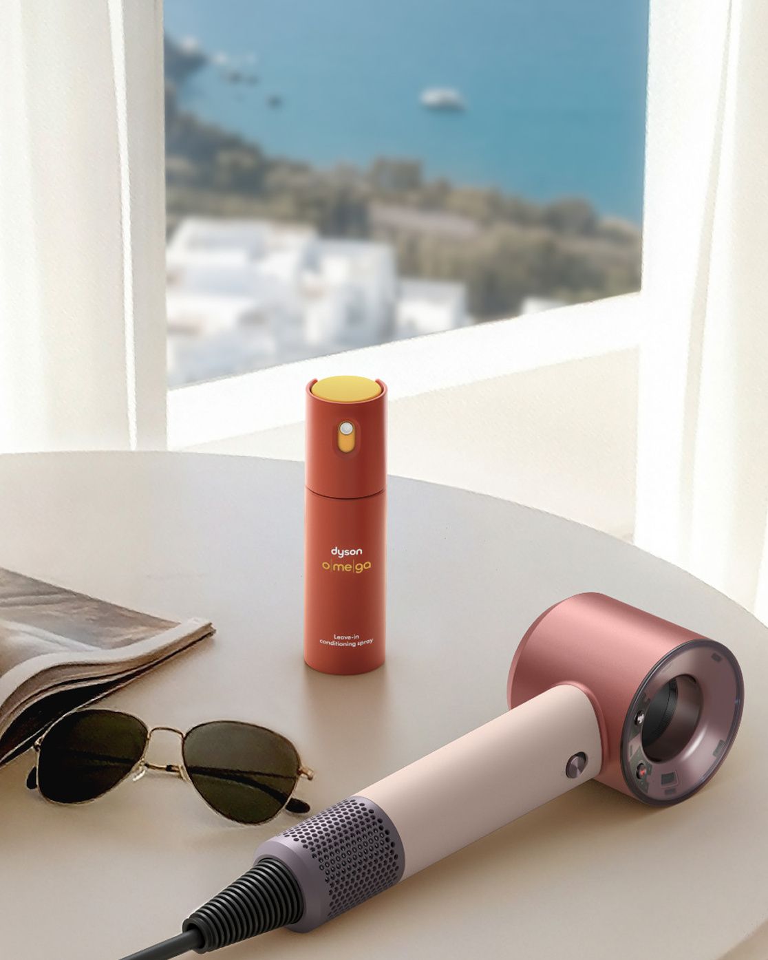 Dyson Supersonic Travel hair dryer on a table next to Dyson Omega leave-in conditioning spray.