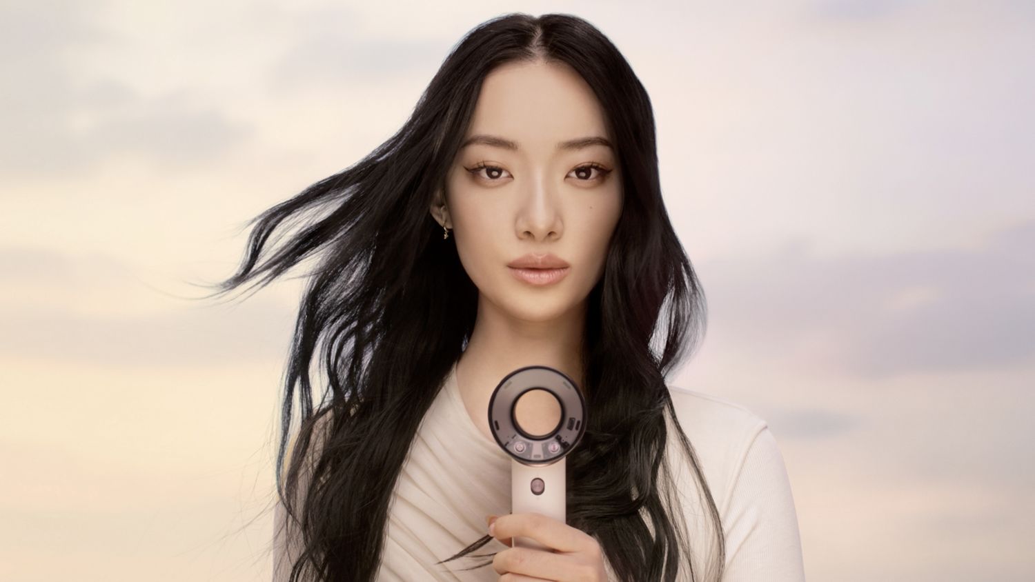 Model holds the Dyson Supersonic Travel hair dryer in front of herself.