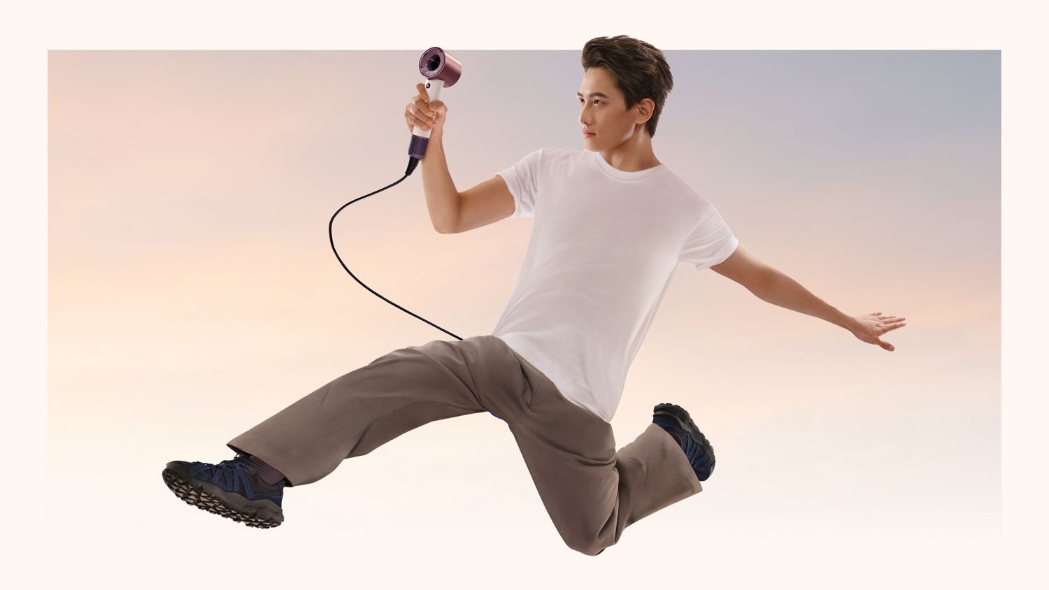ダイソン スーパーソニック トラベル ヘアドライヤーを持って宙にジャンプしているモデル