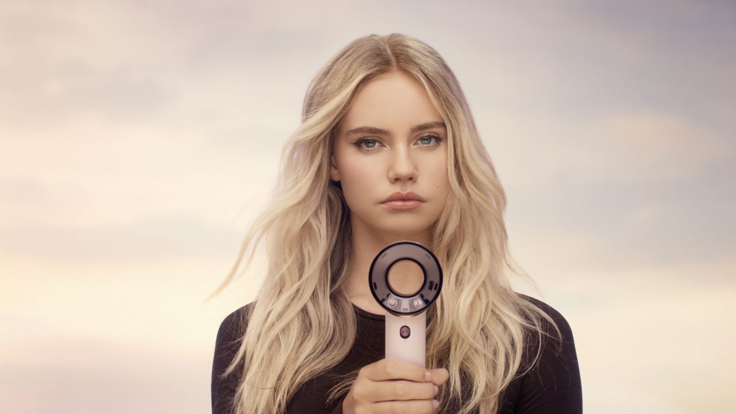 Model holds the Dyson Supersonic Travel hair dryer in front of herself.