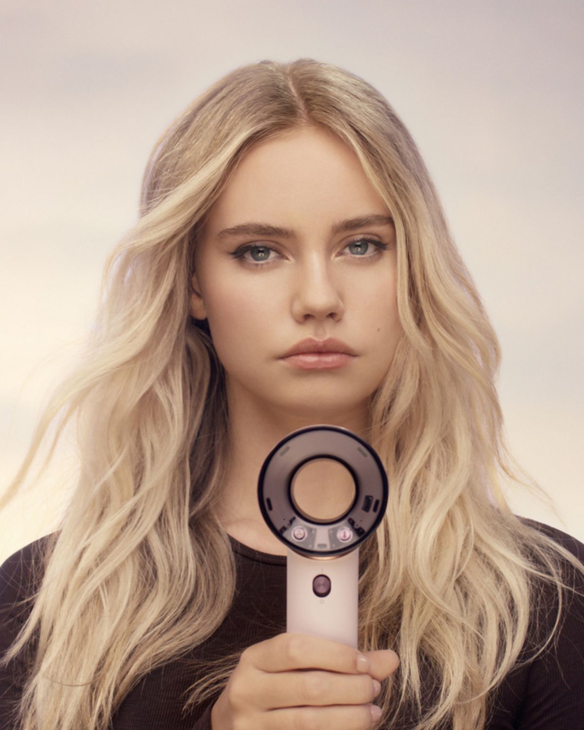 Model holds the Dyson Supersonic Travel hair dryer in front of herself.