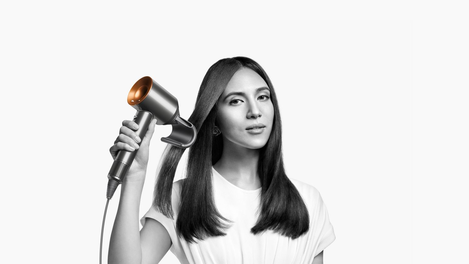 A model smooths her hair with the Flyaway attachment on the Dyson Supersonic hair dryer.