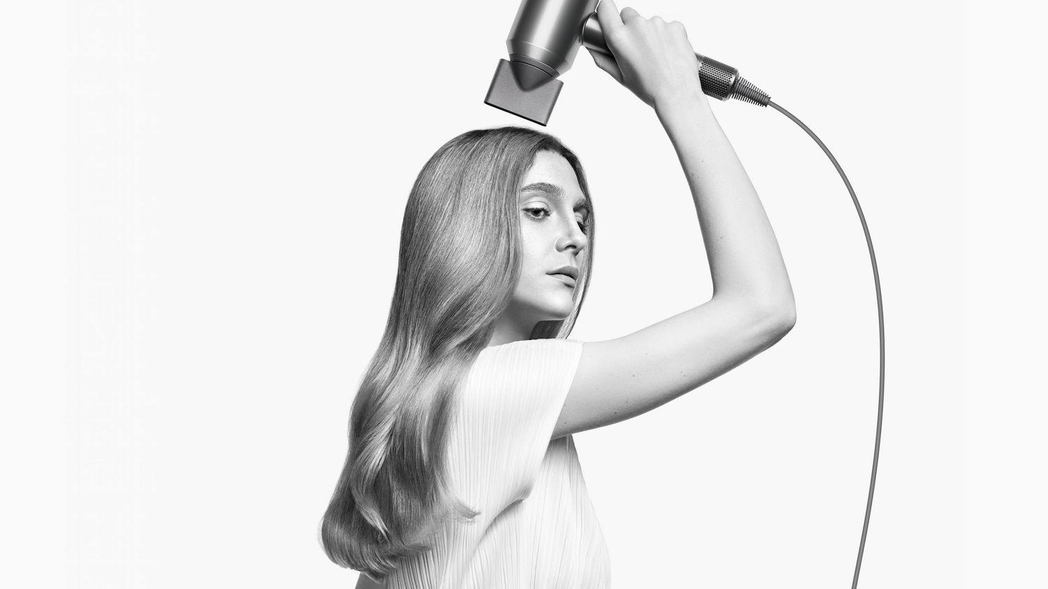 A model styles her hair with the Styling concentrator attachment on the Dyson Supersonic hair dryer.