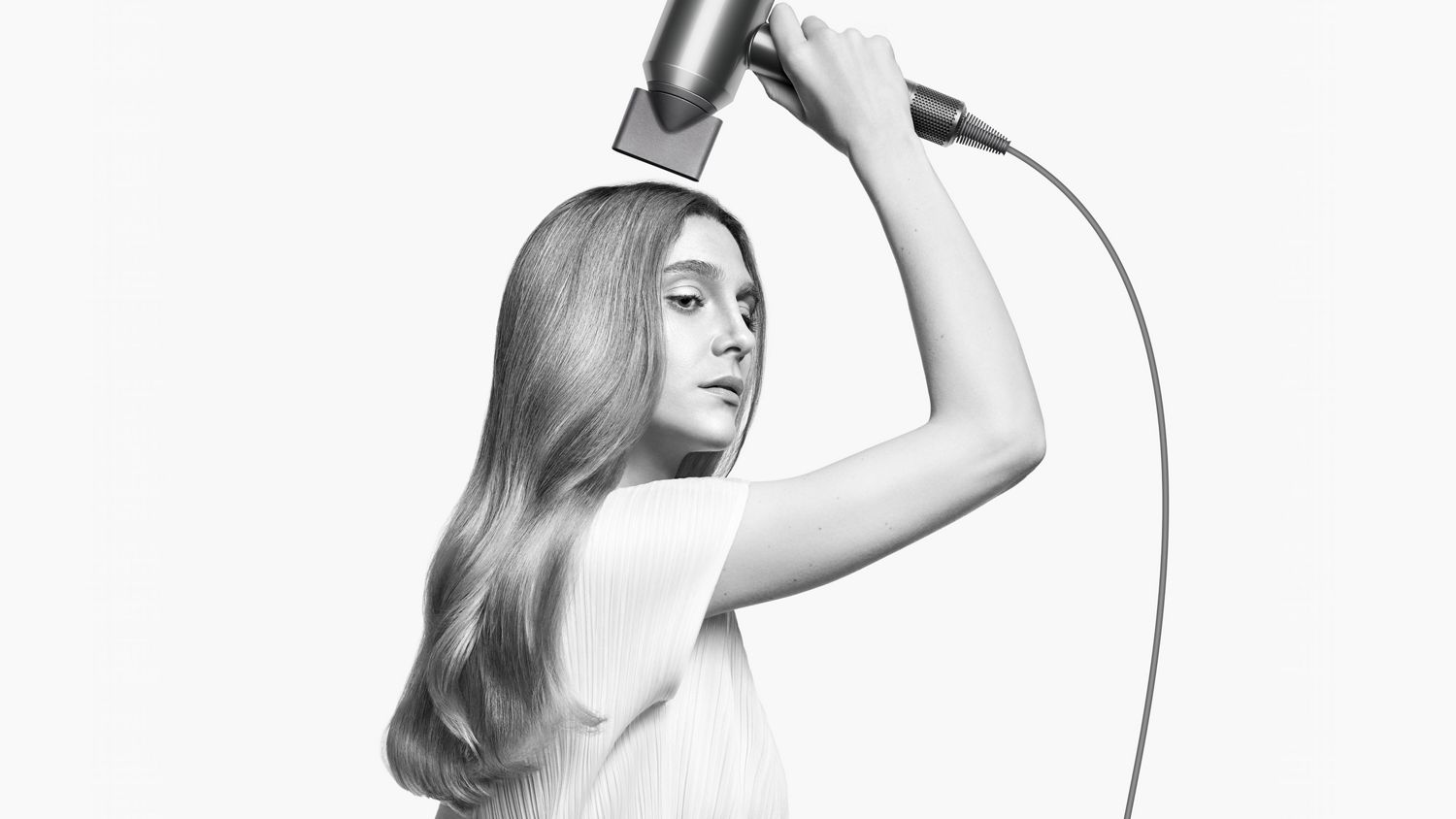 A model styles her hair with the Styling concentrator attachment on the Dyson Supersonic hair dryer.