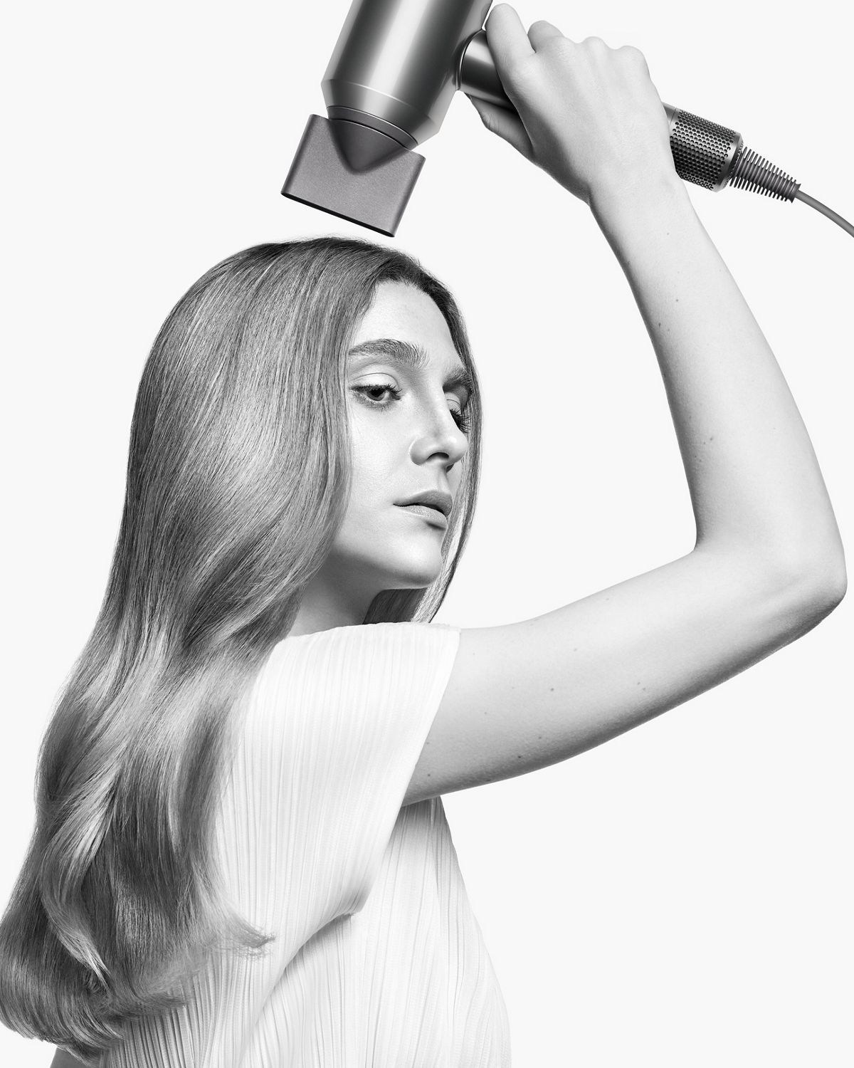 A model styles her hair with the Styling concentrator attachment on the Dyson Supersonic hair dryer.