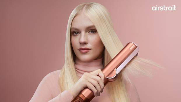 A blonde model dries and styles her hair with the Dyson Airstrait dryer and straightener.