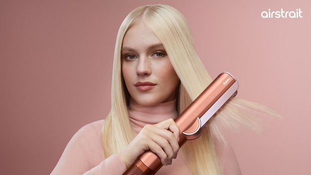 A blonde model dries and styles her hair with the Dyson Airstrait dryer and straightener.
