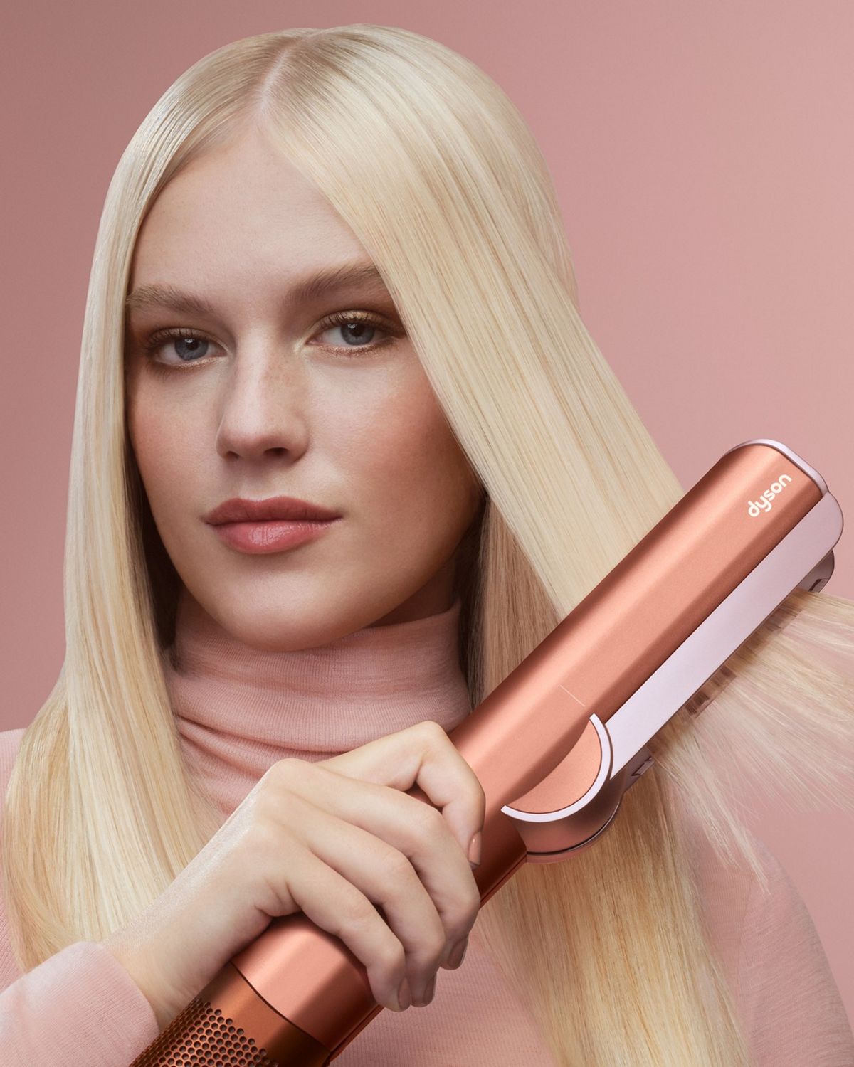  Model styling hair with the Dyson Airstrait.