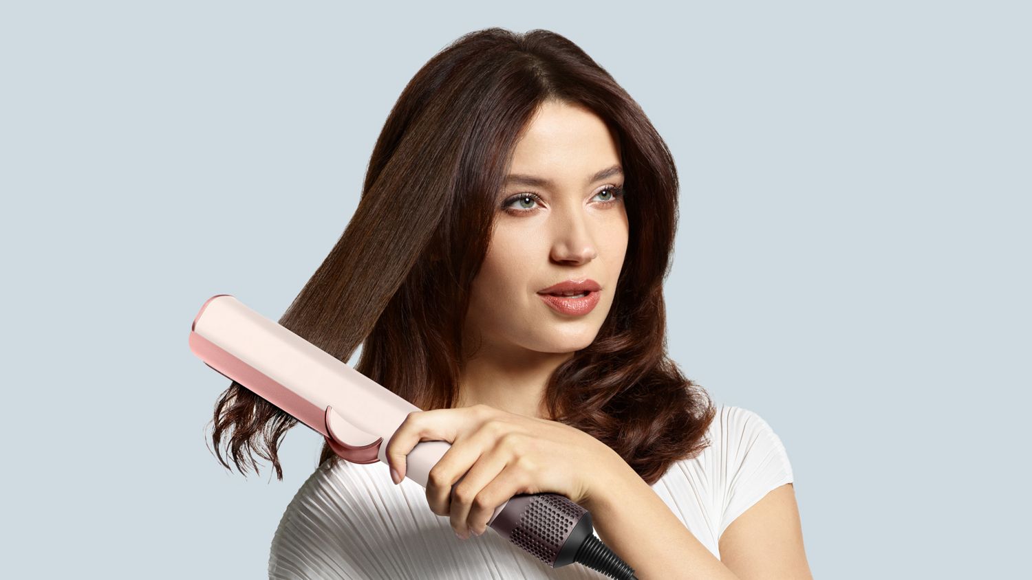 Ein Modell glättet ihr Haar mit dem Dyson Airstrait Haartrockner und -glätter.