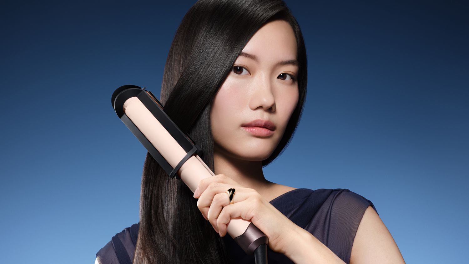 Model straightens her hair with the Dyson Corrale CoolShine hair straightener.