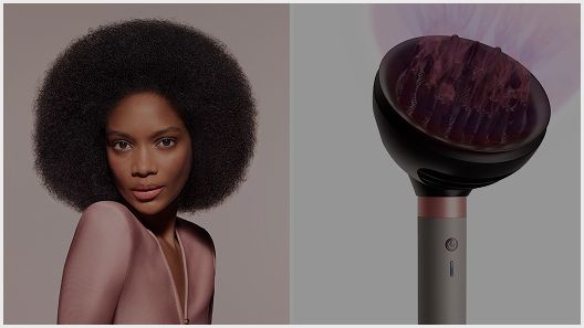 The Dyson Airwrap Co-anda2x multi-styler and dryer with the Wave+Curl diffuser 2x next to a model with dark coily hair.