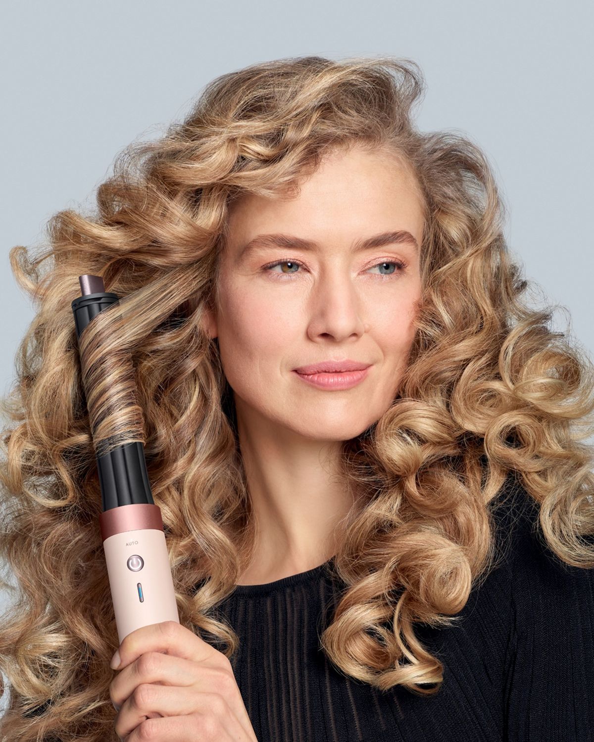 Modelo con cabello ondulado utilizando el moldeador multifunción y secador Dyson Airwrap Co-anda2x.