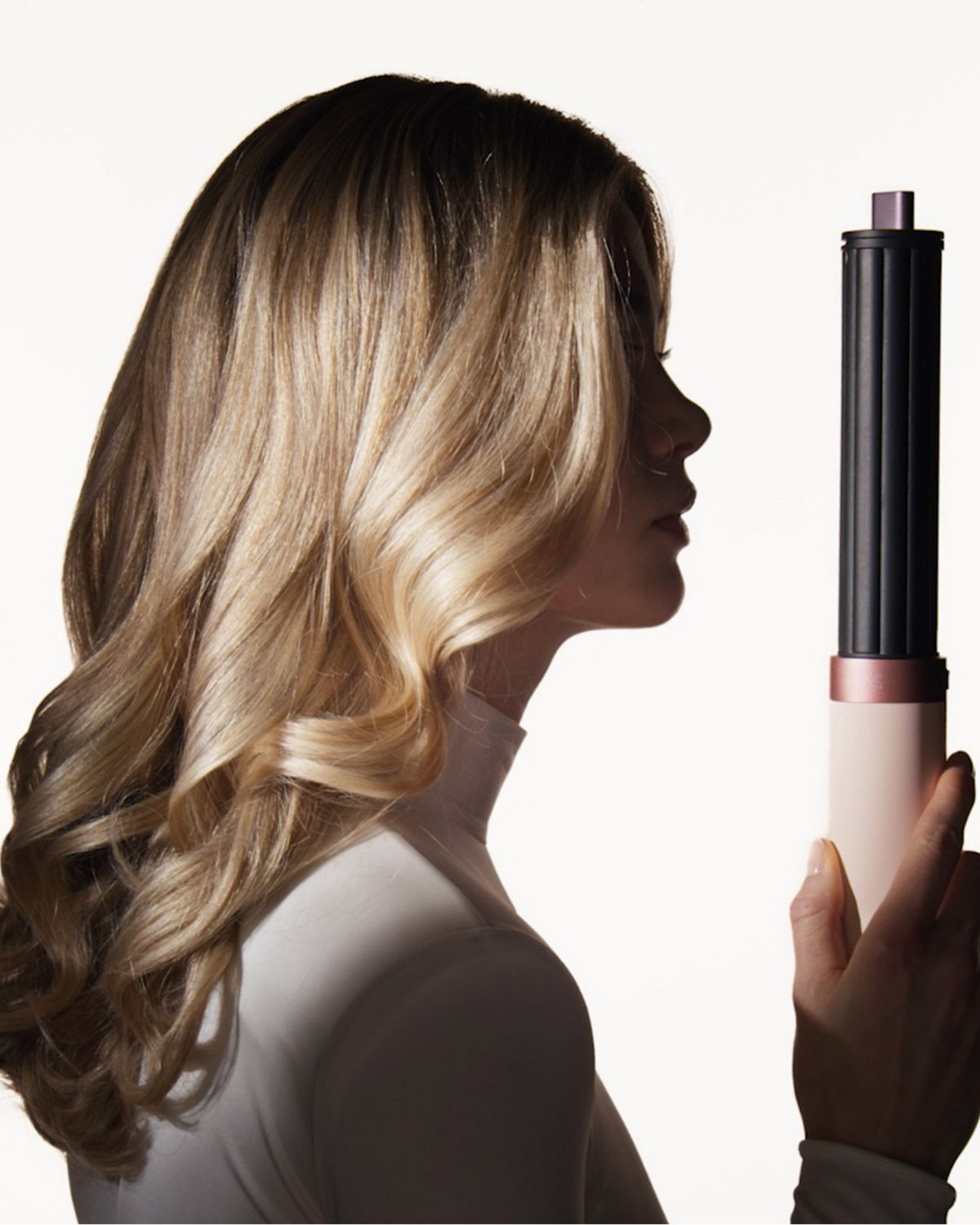 Model next to the Dyson Airwrap Co-anda2x multi-styler and dryer.