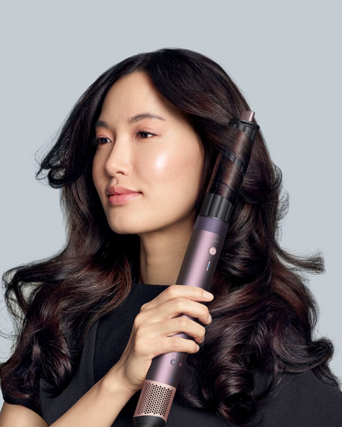 A model with dark hair adds curls using the Dyson Airwrap Co-anda2x multi-styler and dryer. The next-level multi-styler.