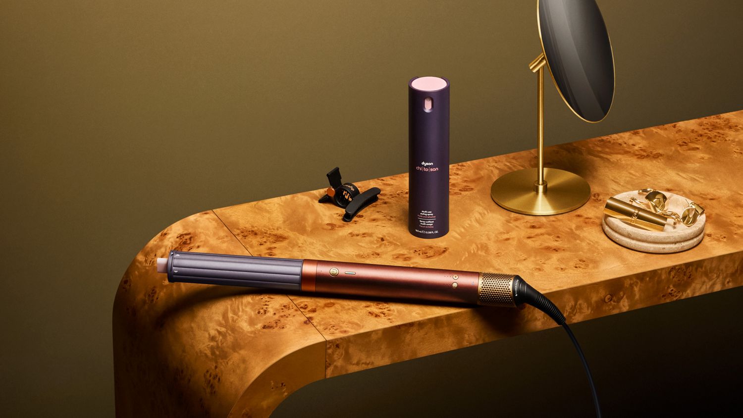 Dyson Airwrap Co-anda2x multi-styler and dryer and Chitosan multi-use styling spray on a table.