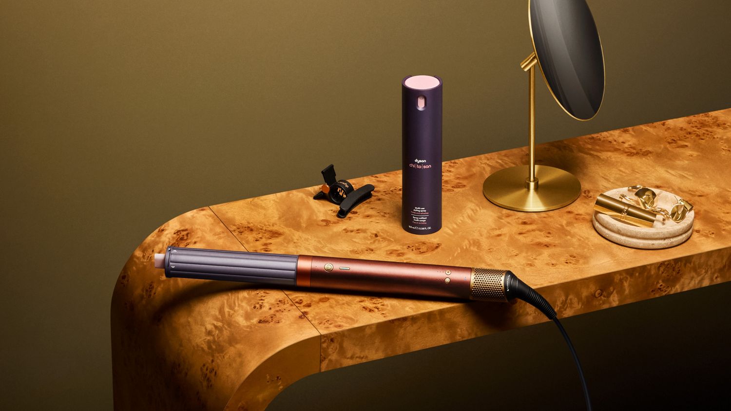 Dyson Airwrap Co-anda2x multi-styler and dryer and Chitosan multi-use styling spray on a table.