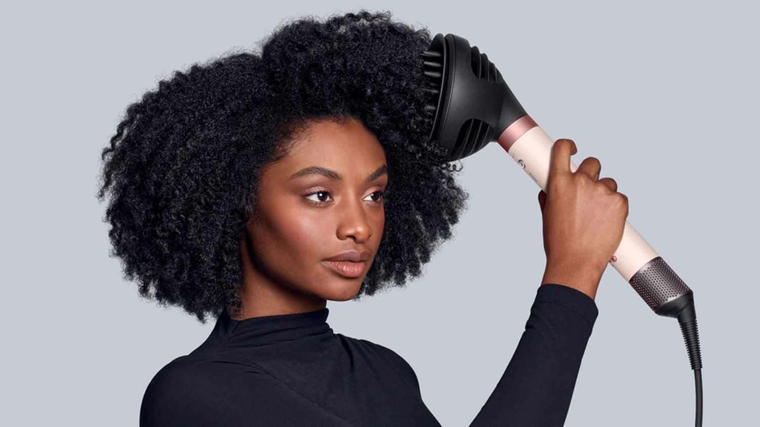 Model with coily hair using the Dyson Airwrap Co-anda2x multi-styler and dryer.