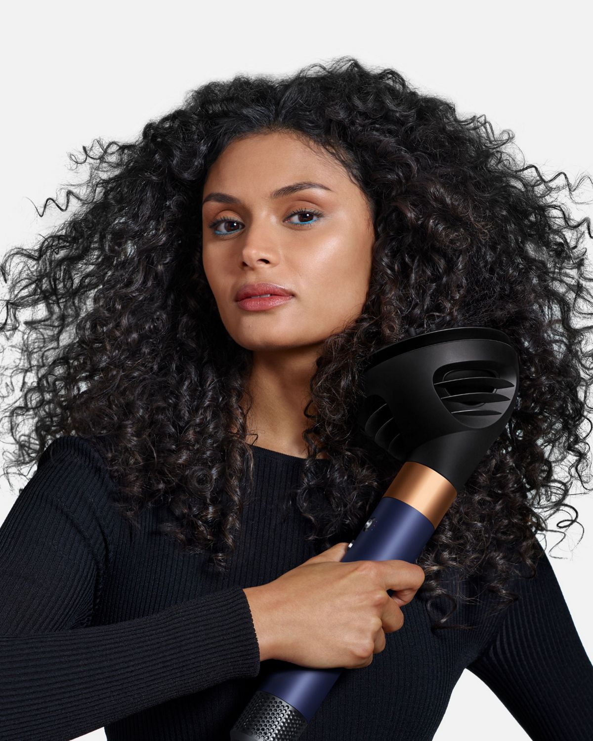 Front-on view of a woman adding volume to her hair with the Dyson Airwrap ID and the Wave+Curl diffuser.