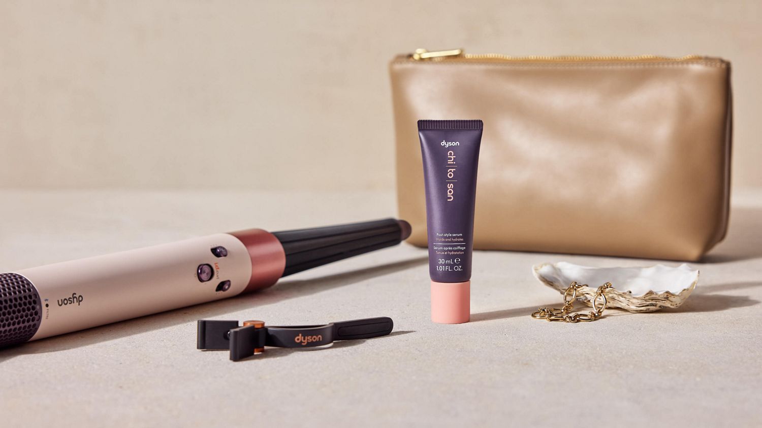 Dyson Airwrap i.d. multi-styler and dryer next to Dyson Chitosan post-style serum mini and a makeup bag.