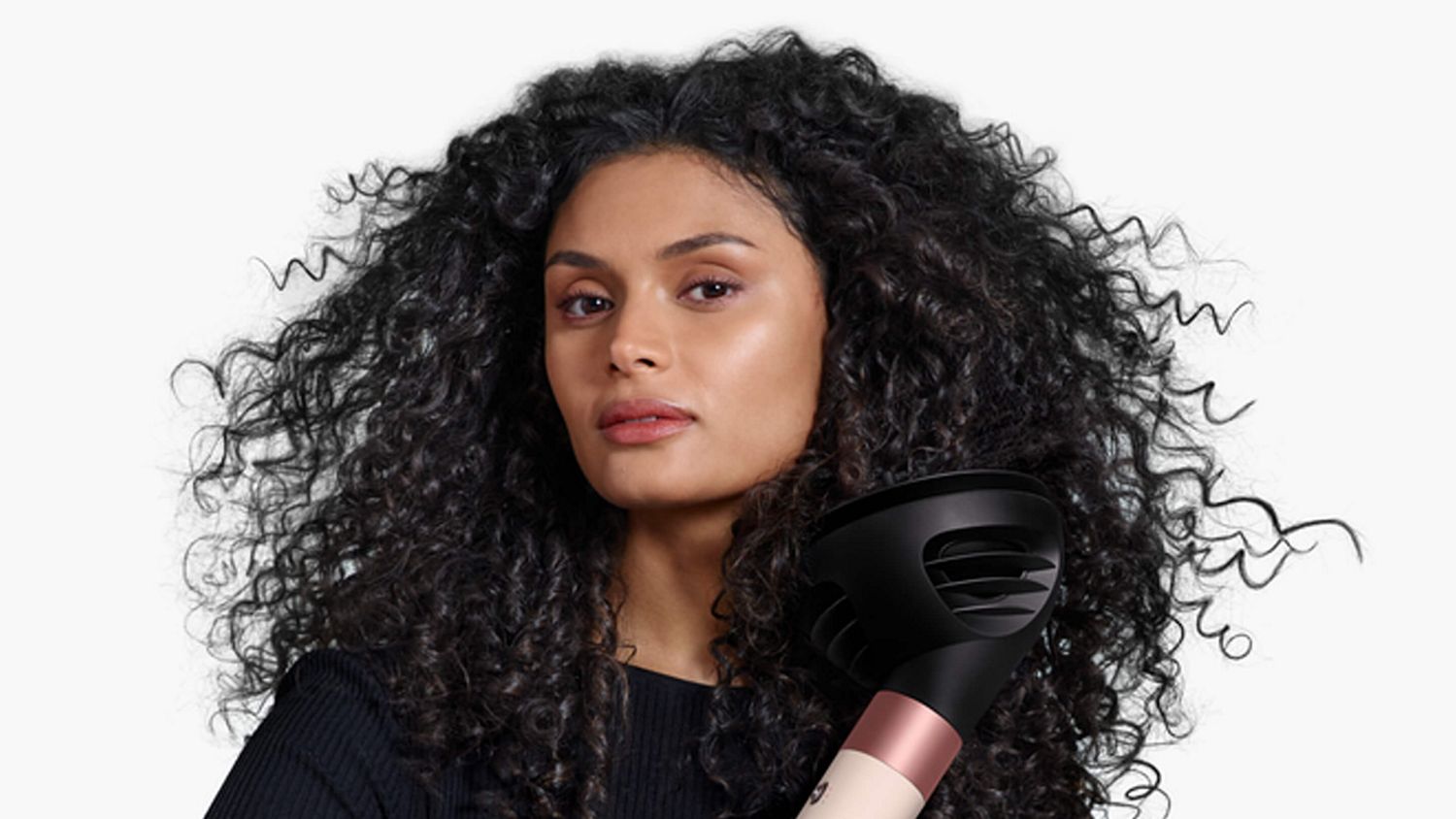 Model with curly hair styling hair with the Dyson Airwrap i.d. multi-styler and dryer.