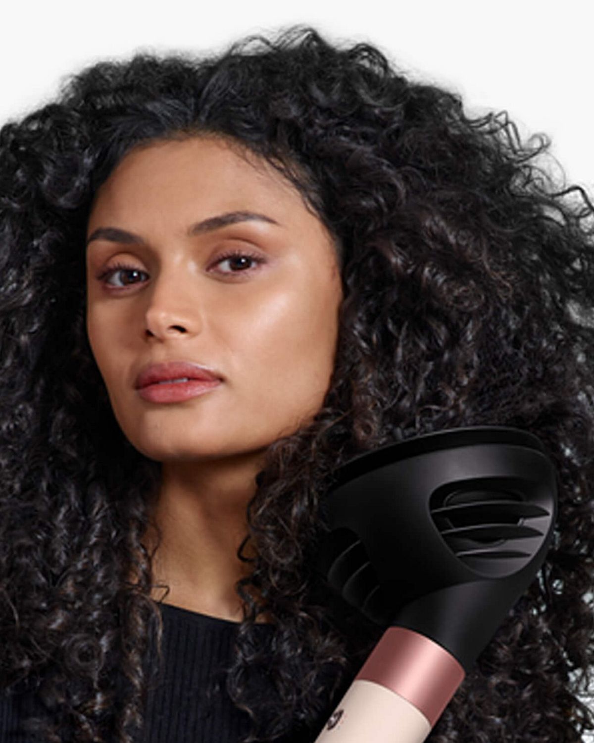 Model with curly hair styling hair with the Dyson Airwrap i.d. multi-styler and dryer.