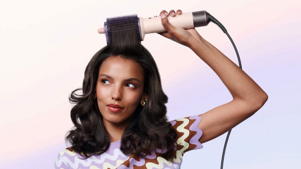 Model styles her hair with the Dyson Airsmooth styling brush.