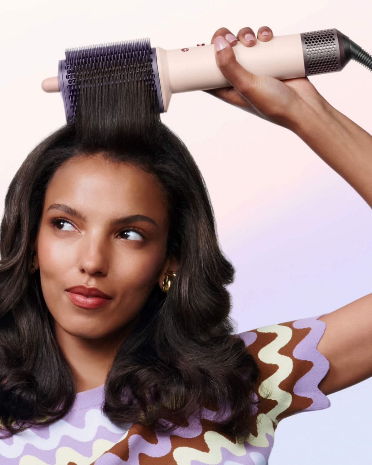 Model styles her hair with the Dyson Airsmooth styling brush.