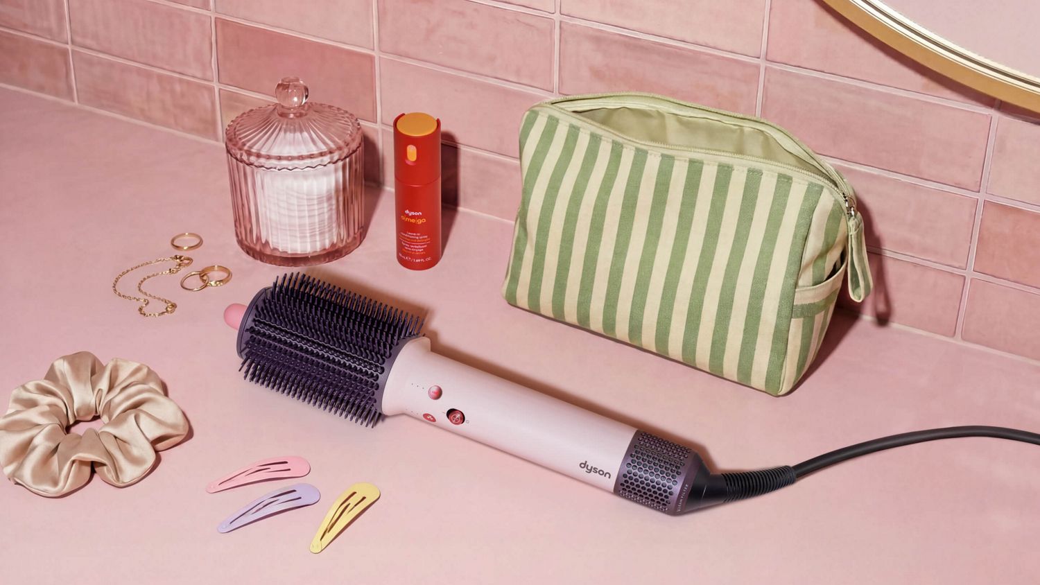 Dyson Airsmooth styling brush next to hair clips and a toiletries bag.