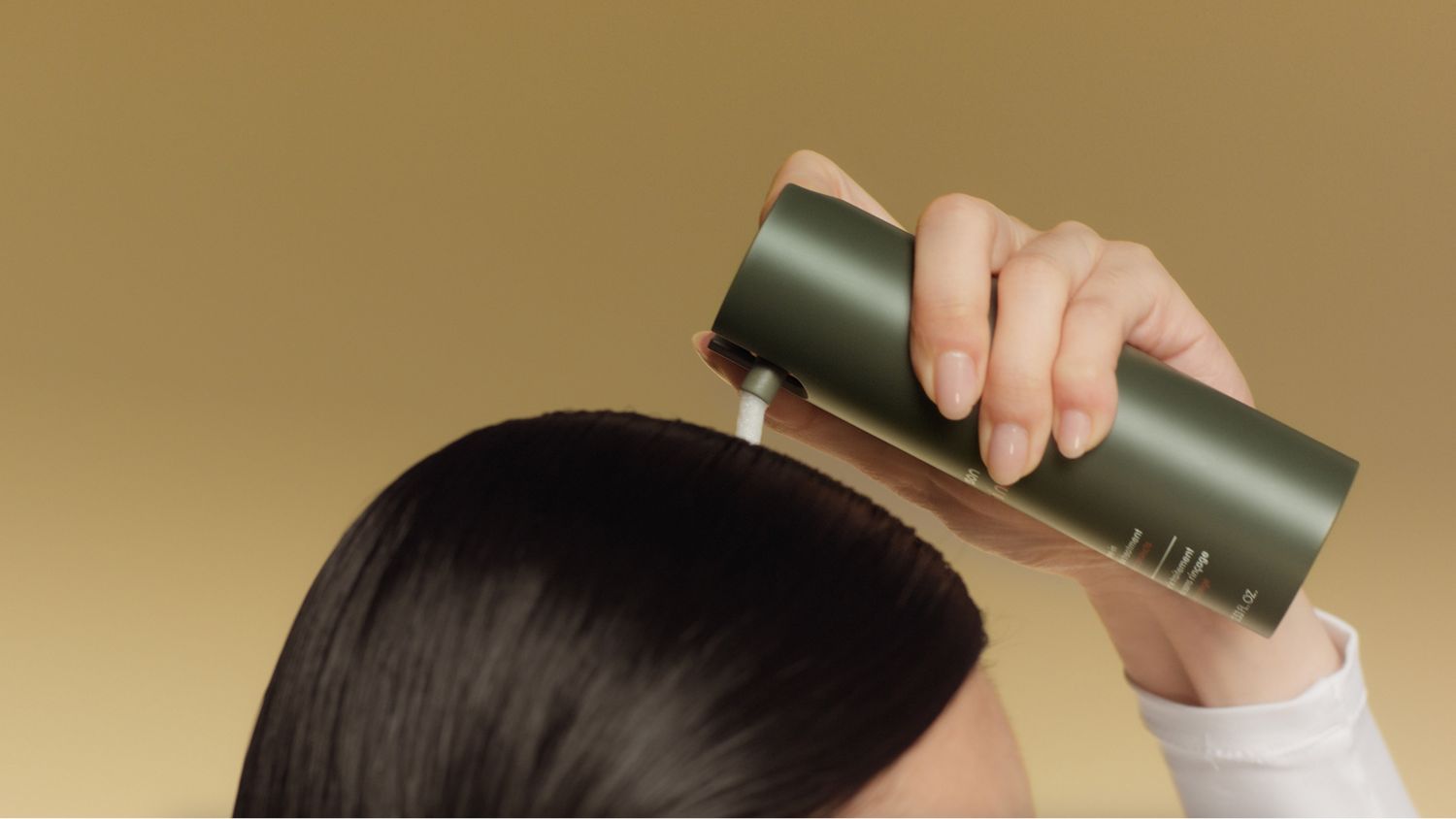 A model applies Dyson Amino leave-in scalp bubble treatment to her scalp.