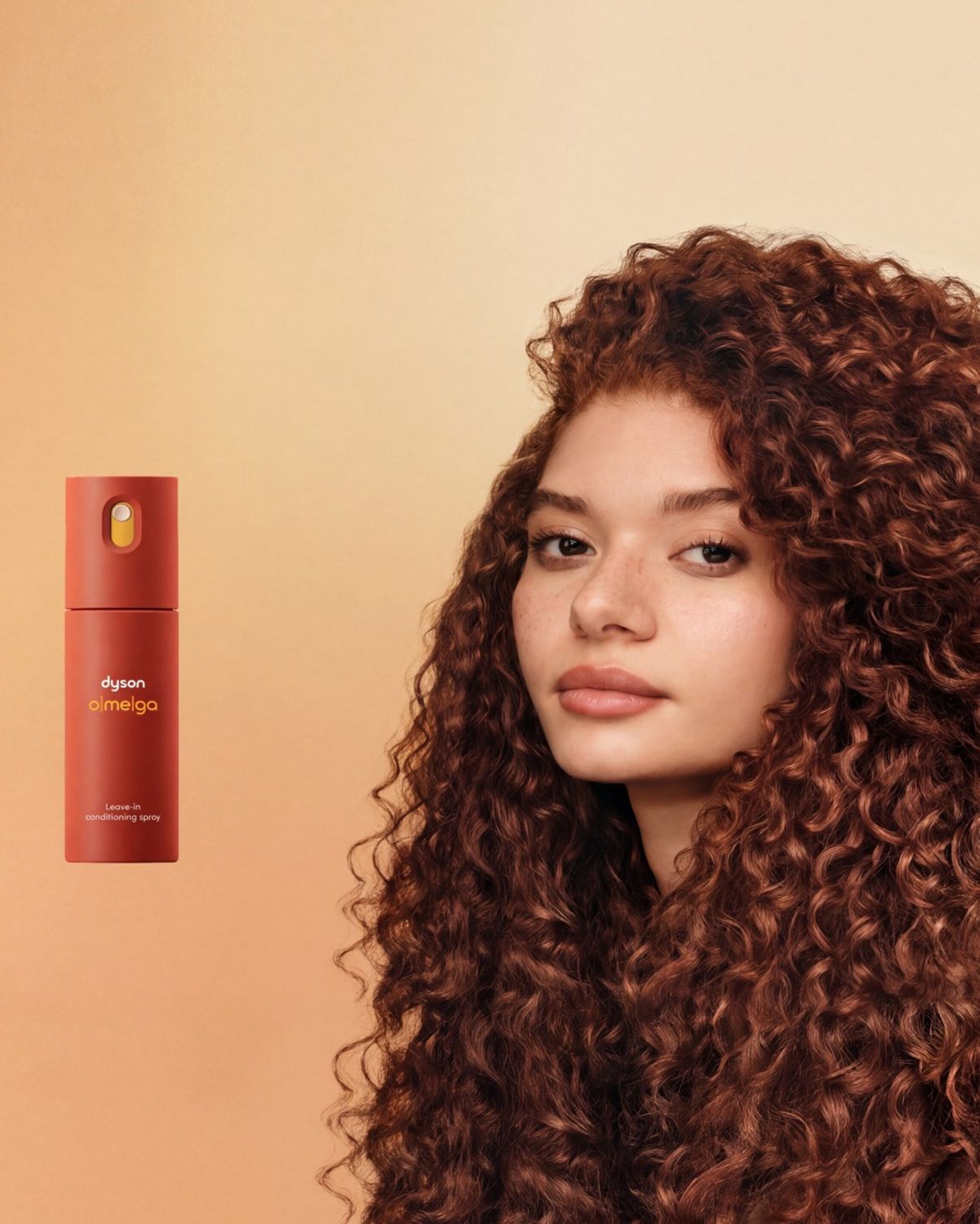 The Dyson Omega leave-in conditioning spray next to a model with styled curly hair.