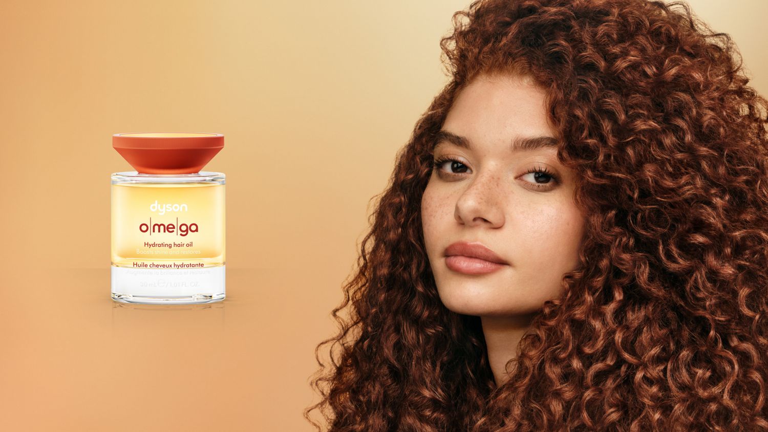 The Dyson Omega hydrating hair oil next to a model with styled curly hair.
