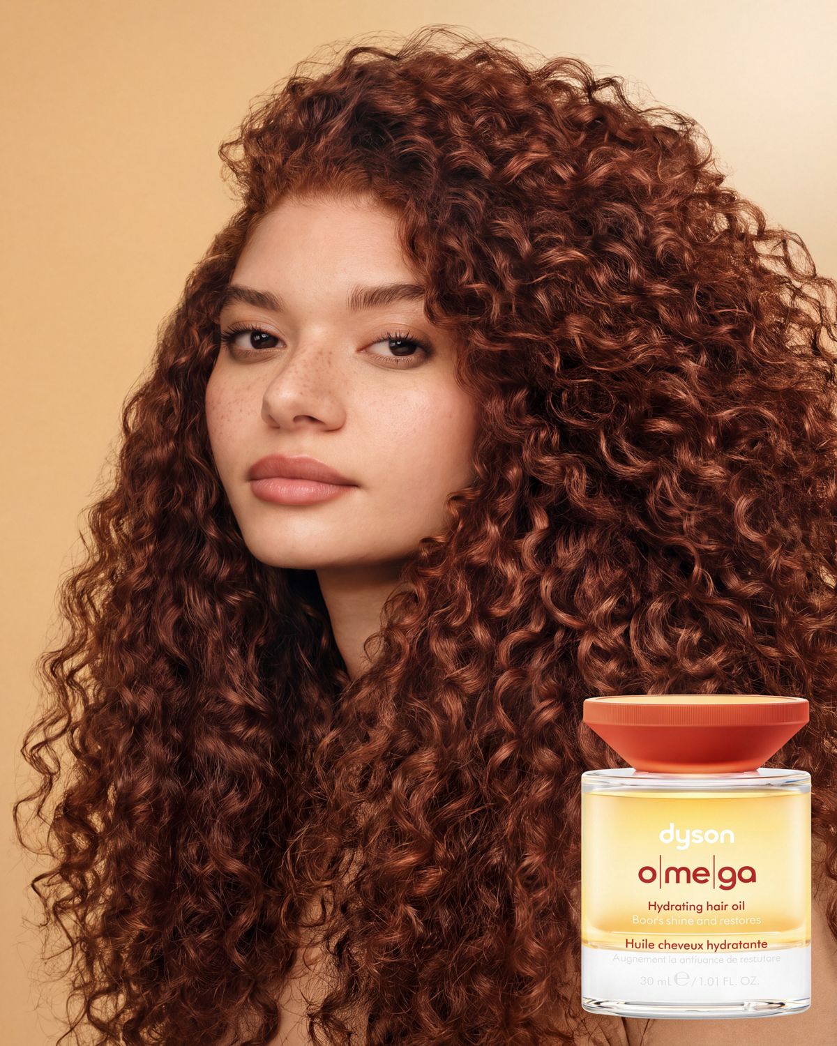 The Dyson Omega hydrating hair oil next to a model with styled curly hair.