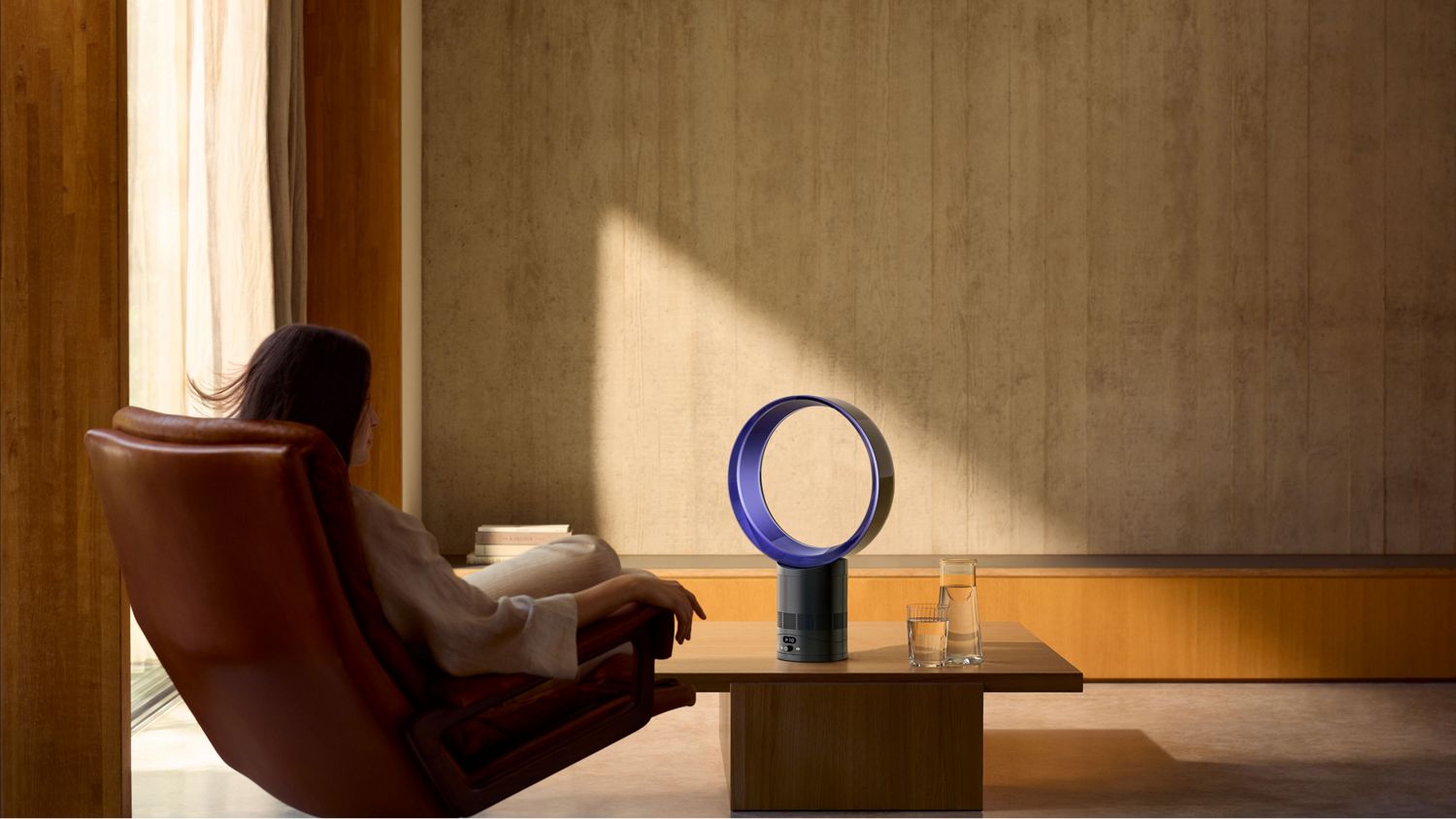 The Dyson Cool CF1 delivering a cool breeze to a person relaxing in a chair.