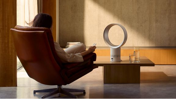 Der Dyson Cool CF1 erzeugt eine kühlende Brise für eine Person, die sich in einem Sessel entspannt.