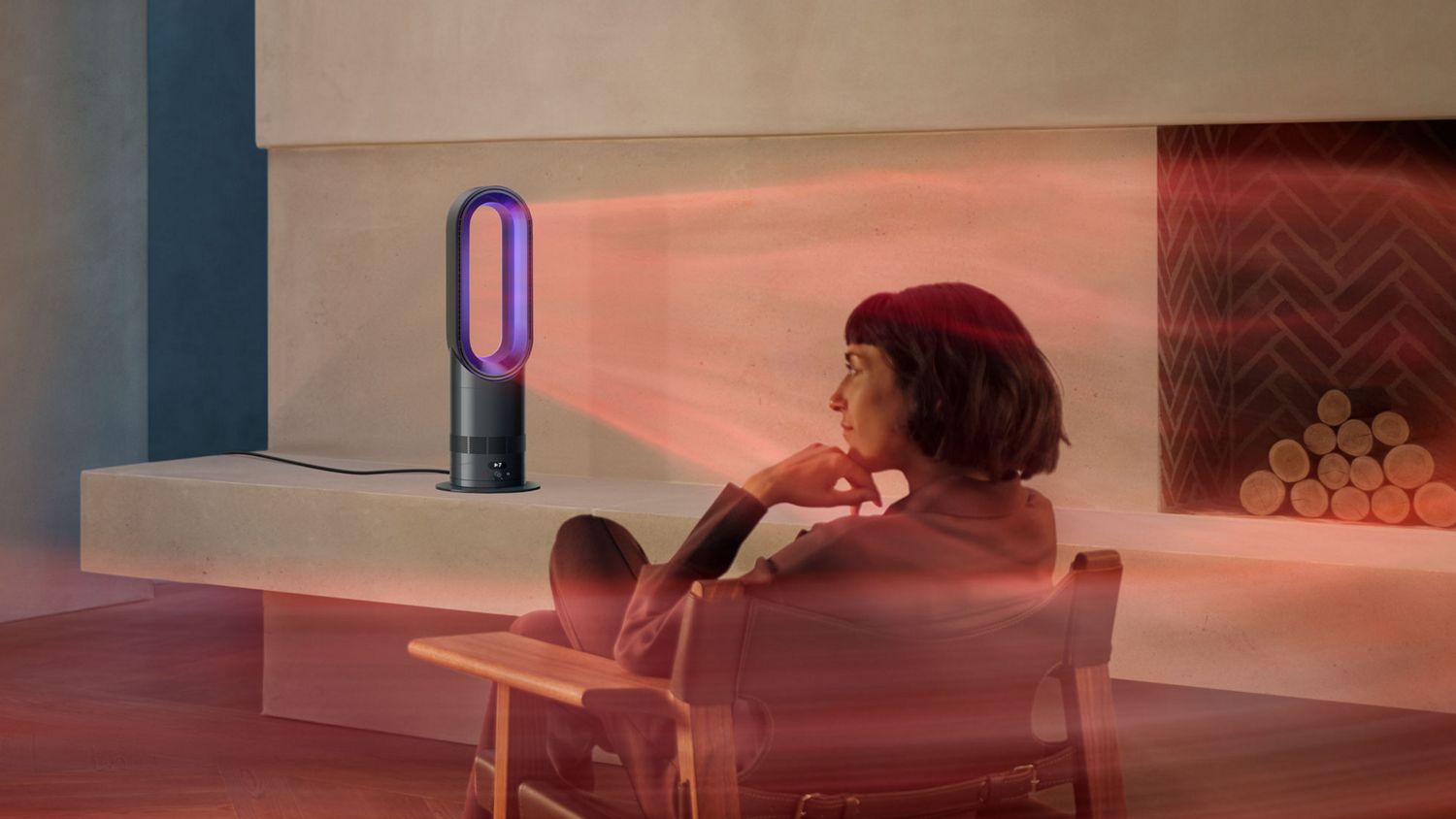 A woman sits in front of her Dyson Hot+Cool HF1 Rapid React heater and cooling fan as it heats the room.