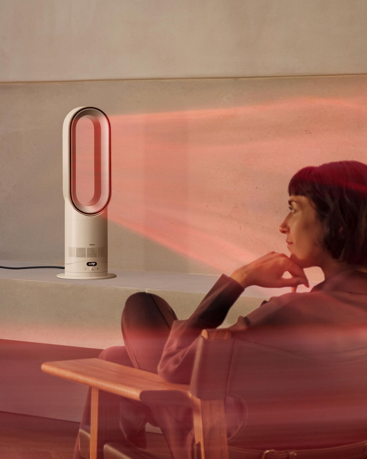 A woman sits in front of her Dyson Hot+Cool HF1 Remote Link Pre-heat heater and cooling fan as it heats the room.