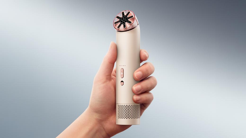 The Dyson HushJet Mini Cool portable fan held upright in a hand.