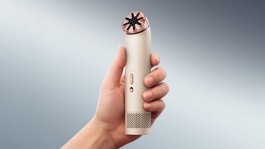 The Dyson HushJet Mini Cool portable fan held upright in a hand.