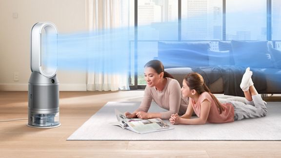 Mutter und Tochter liegen auf einem Teppich mit Dyson Purifier Humidify+Cool Autoreact, der sie kühlt