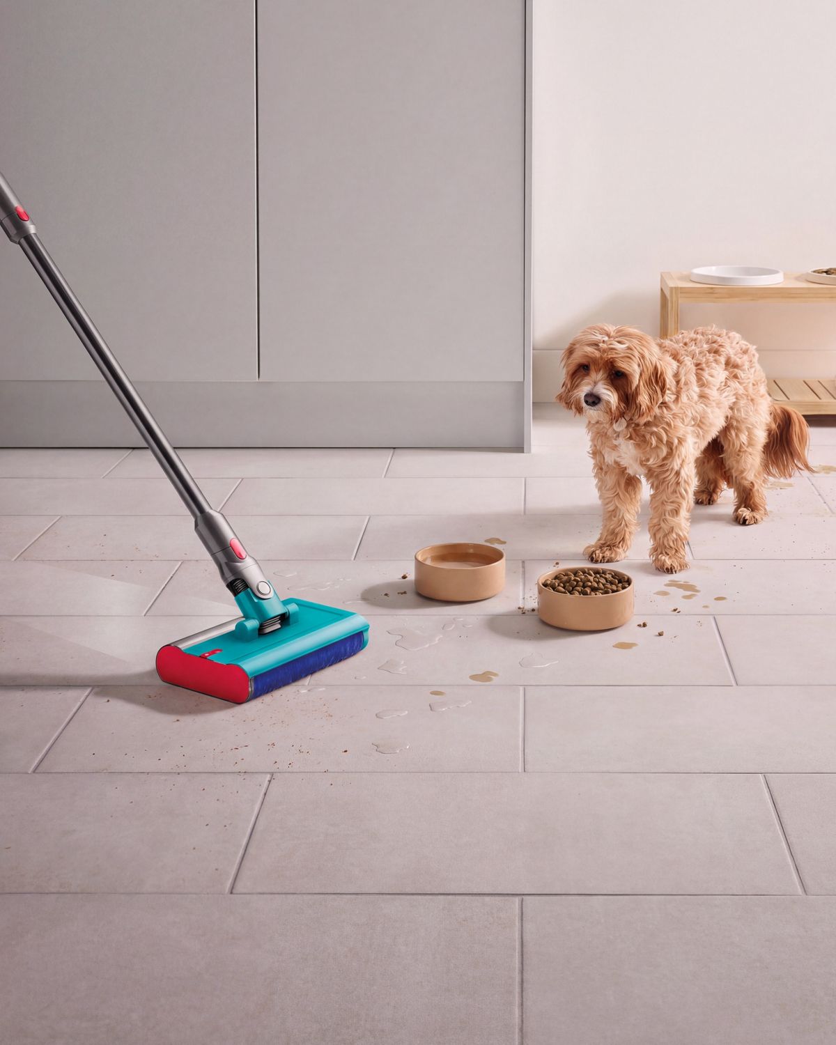 A Dyson vacuum with the Submarine wet roller head is used by a pet owner to clean a spill from their dog’s bowl.