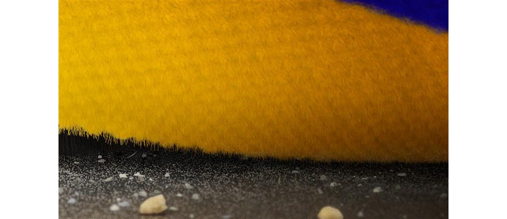 Close-up of the Dyson Fluffy Optic cleaner head’s brush bar as it cleans into a crevice on a hard floor.