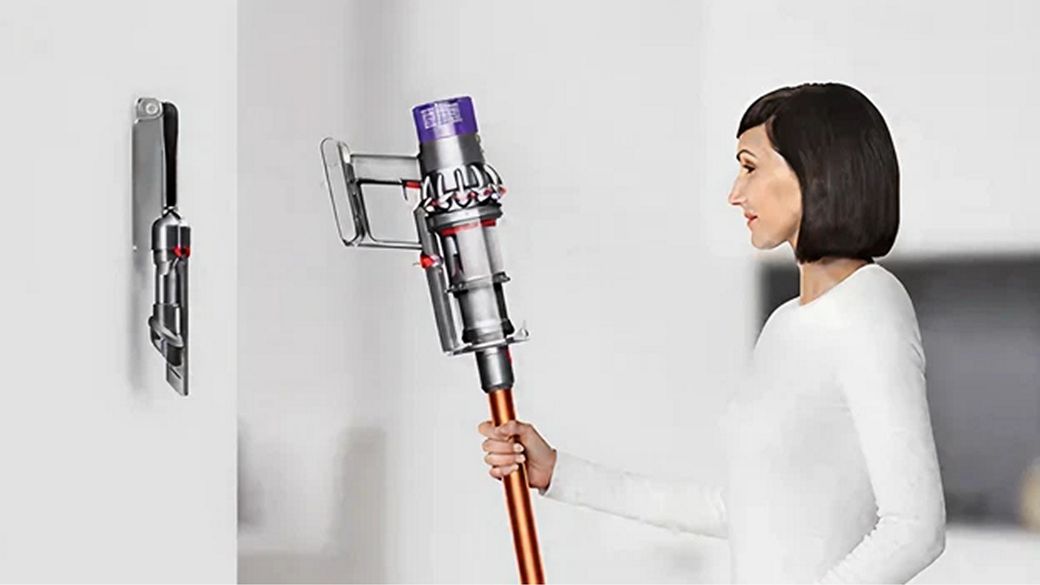 Dyson Cyclone V10 putekļu sūcējs ir novietots pie sienas piestiprinātā uzlādes dokstacijā.