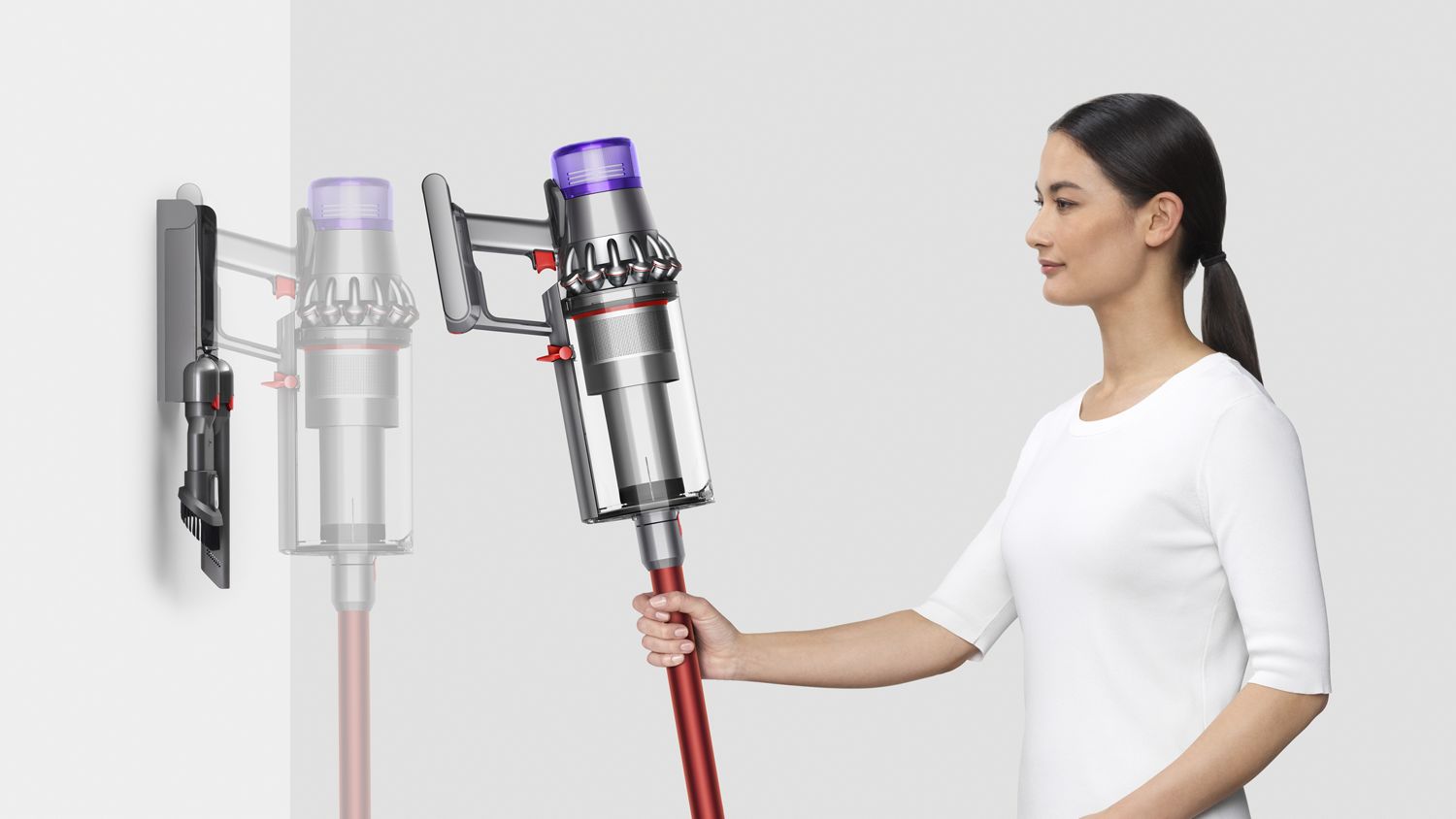 Woman placing Dyson Outsize vacuum into wall charging dock