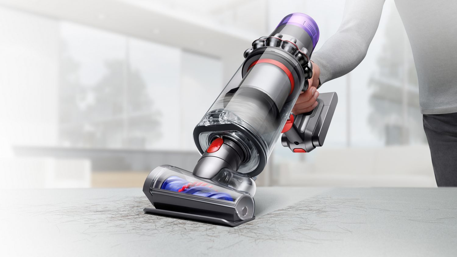 A Dyson V11 cordless vacuum cleaner in handheld mode with Hair screw tool removing pet hair from upholstery