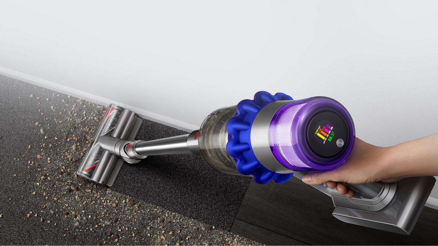An aerial view of the Dyson V15 Detect vacuum picking up dust against a wall.